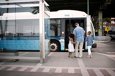 Older person entering bus with two children