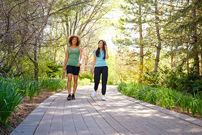 Two women walking on a paved path